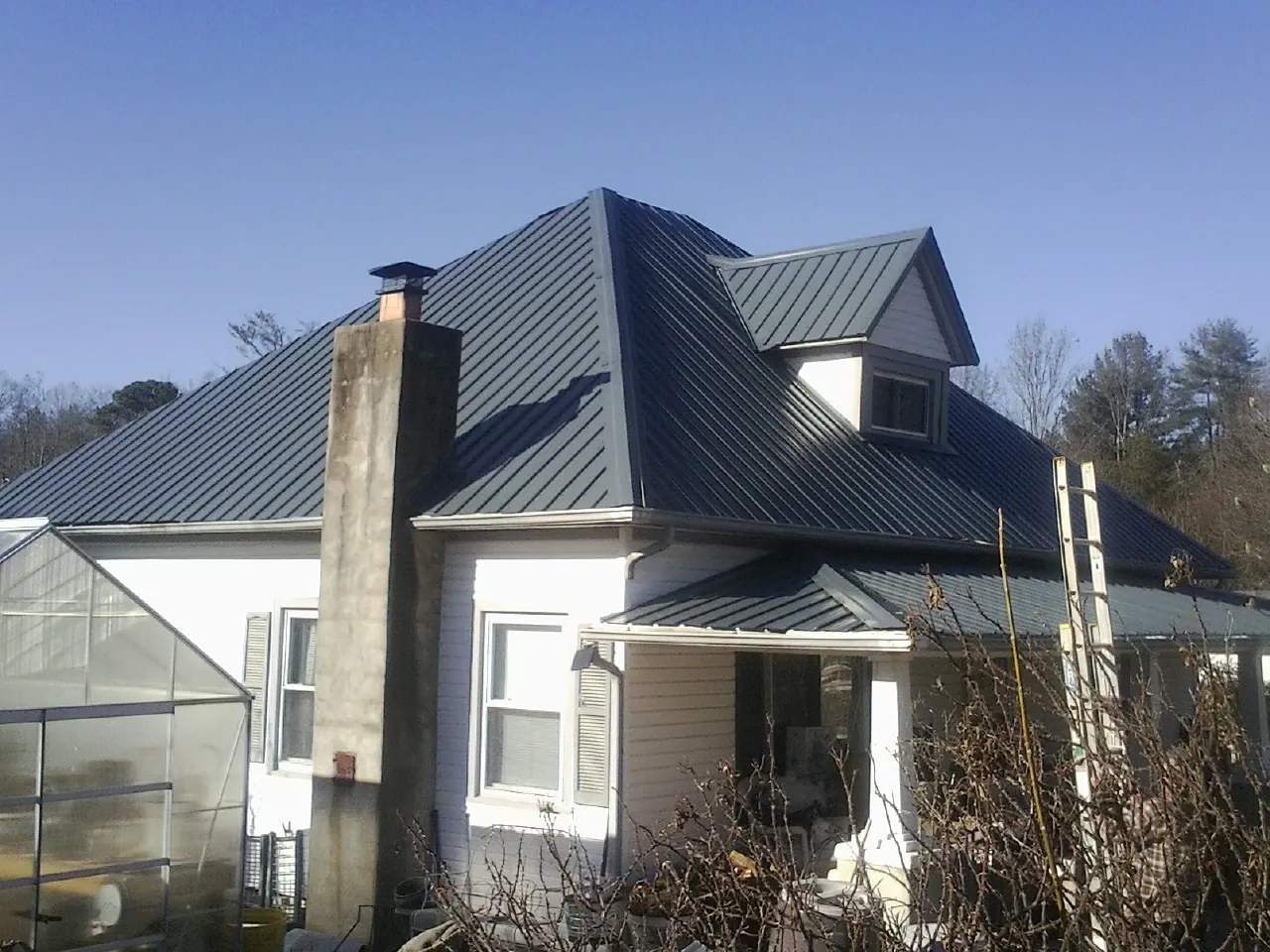 Dark blue standing seam metal roof on a white farmhouse with dormer — Slate & Tile Roof Repair by Roofing Brothers in Laurel Springs