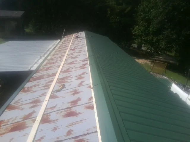 Old rusted panels beside newly installed green metal roofing — Wind Damage Roof Repair by Roofing Brothers in Laurel Springs