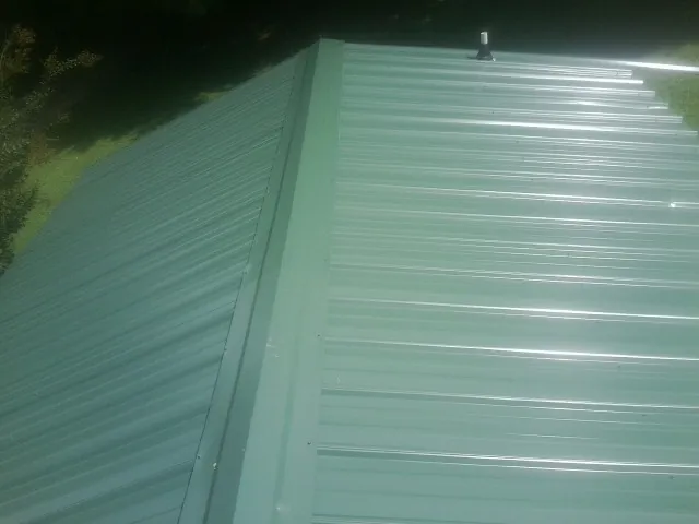 New green metal panels meeting at the ridge of a roof — Flat Roof Repair work by our crew in Laurel Springs