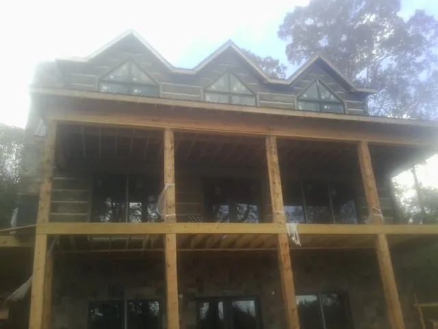 Dormers and porch framing on a large log home under construction — Roof Coating work by our crew in Laurel Springs