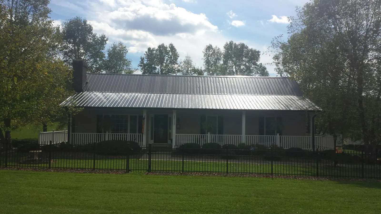 Gray metal roof on a brick ranch with a full width front porch — Gutter Guard Installation work by our crew in Laurel Springs