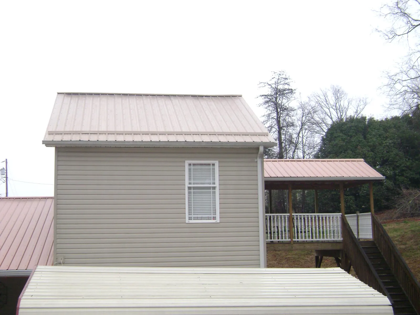 Tan metal roofs on a two story addition and attached porch, from a Roof Replacement job in Laurel Springs