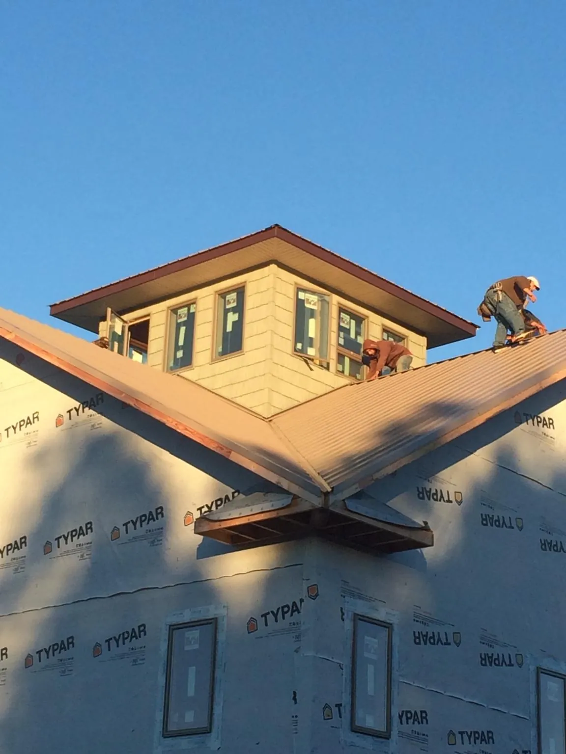 Roofers working around a rooftop cupola on a new metal roof at sunset — Roof Waterproofing in Laurel Springs by Roofing Brothers